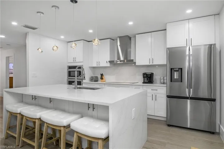 Kitchen with stainless steel appliances, pendant lighting, wood tiled floors, backsplash, and recessed lighting