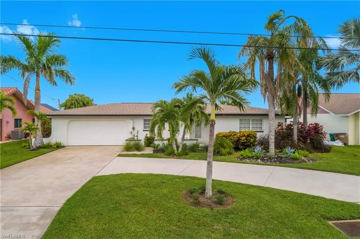 Ranch-style home featuring driveway, a front lawn, and stucco siding