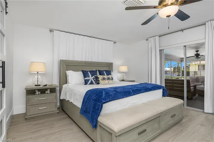 Bedroom with access to outside, light wood-style floors, ceiling fan, and a barn door