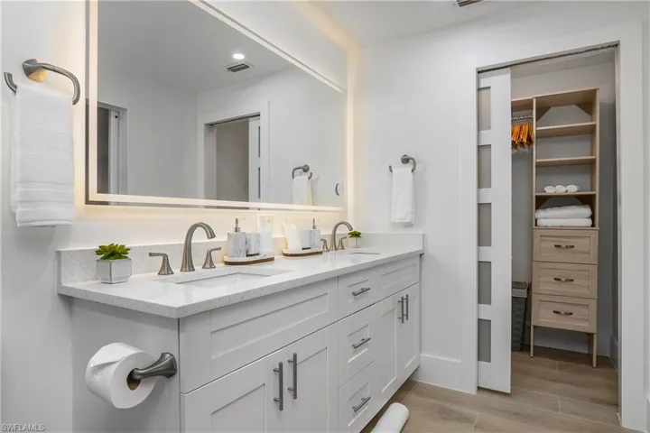 Bathroom with double vanity, wood finish floors, recessed lighting, and a walk in closet