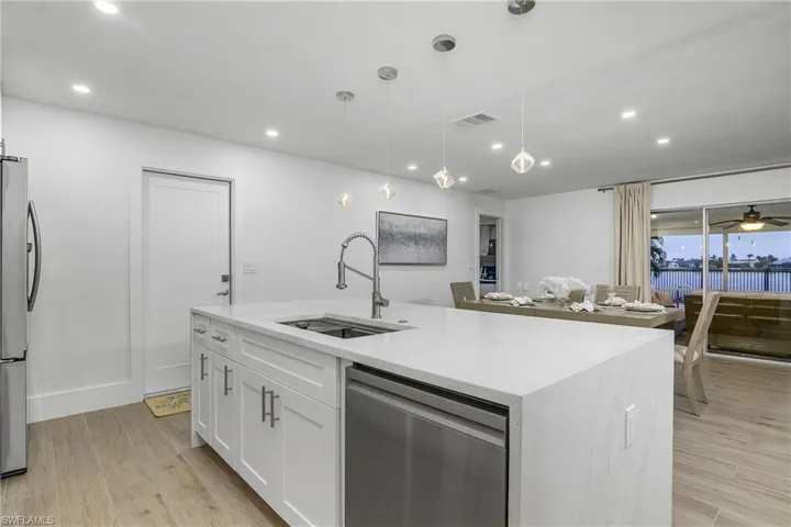 Kitchen with stainless steel appliances, pendant lighting, light wood-style floors, light stone counters, and recessed lighting