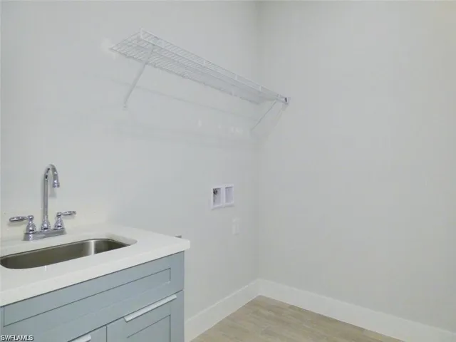 Laundry room with light hardwood / wood-style floors, sink, cabinets, and washer hookup
