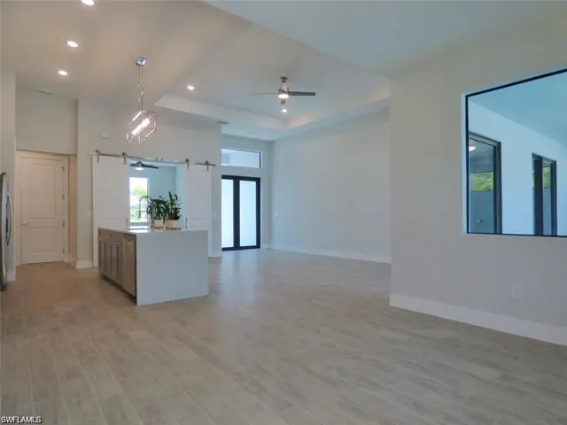 Kitchen with ceiling fan, a raised ceiling, light hardwood / wood-style flooring, and a barn door