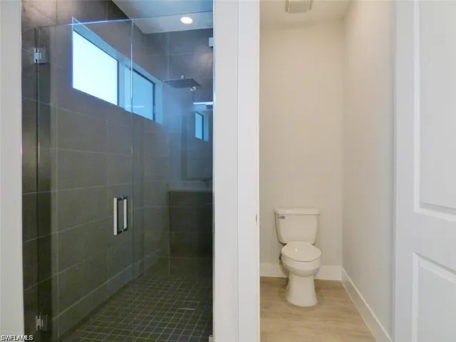 Bathroom featuring walk in shower, wood-type flooring, and toilet