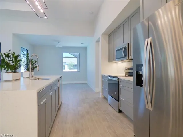 Kitchen featuring appliances with stainless steel finishes, sink, light wood-type flooring, and gray cabinetry