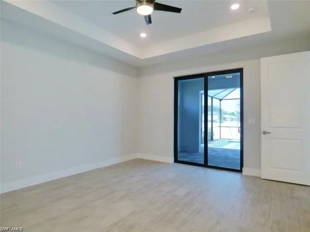 Spare room with ceiling fan, a tray ceiling, and light hardwood / wood-style flooring