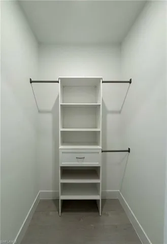 Walk in closet with hardwood / wood-style flooring