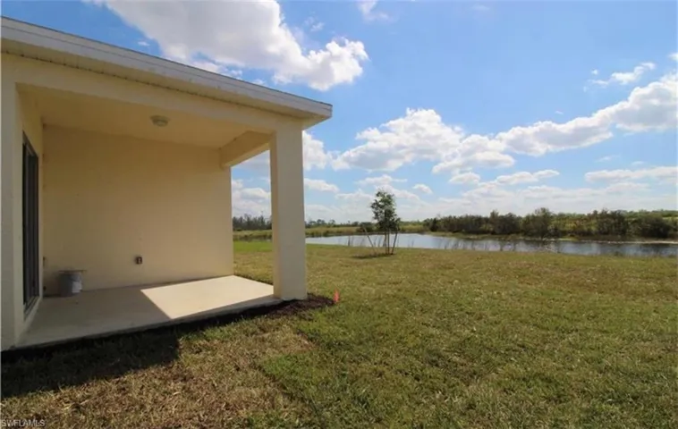 View of green lawn featuring a patio and a water view