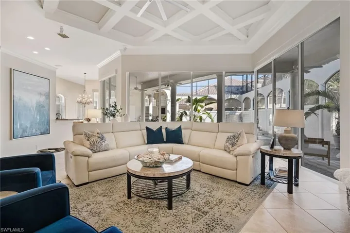As you step into this Kingon Homes masterpiece, a wall of 12-foot sliders frames views of the sparkling pool, outdoor fireplace, and fully equipped gourmet kitchen, all set beneath a soaring coffered ceiling and an abundance of covered lanai space.
