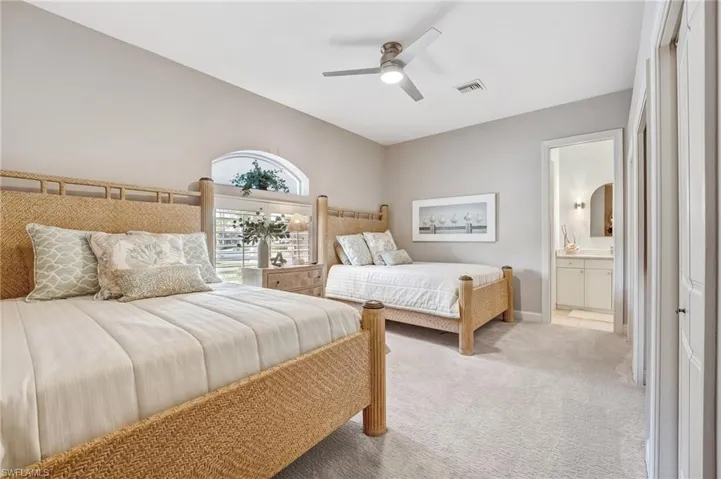 Your generously proportioned second bedroom offers the comfort of plush carpeting, dual closets, and an elegant ensuite bath with a walk-in shower. Plantation shutters frame the windows as natural light pours in, creating a bright and inviting retreat.