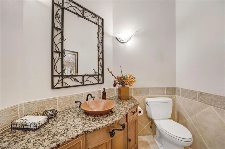 A guest half-bath is conveniently located just outside the office on the first level, featuring custom cabinetry and granite countertops.