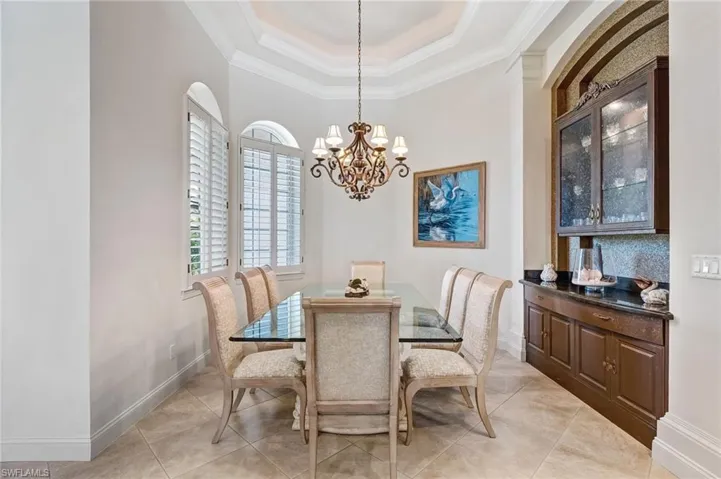 The formal dining room is graced with a double tray ceiling accentuated by uplighting, creating an elegant and inviting ambiance.
