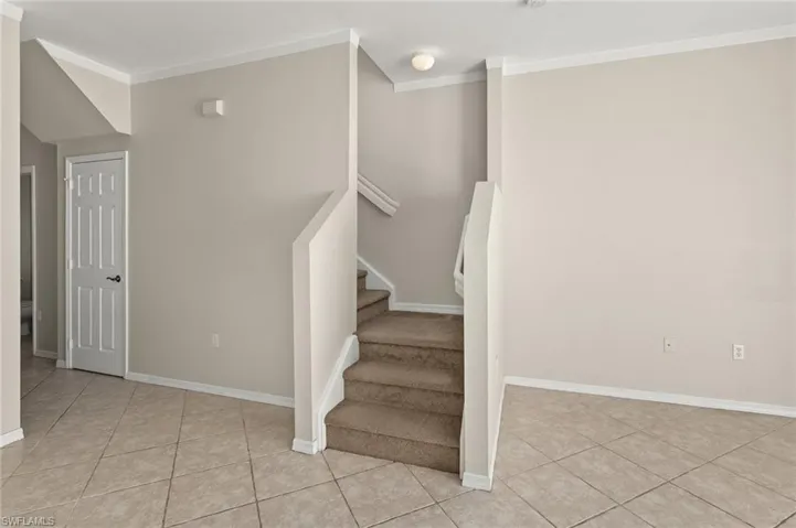 Staircase with tile patterned flooring and crown molding