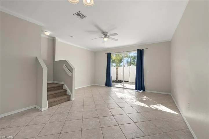 Empty room featuring crown molding, ceiling fan, and light tile patterned floors