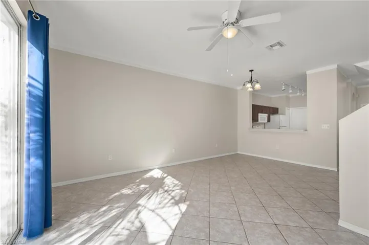 Unfurnished room featuring ornamental molding, ceiling fan with notable chandelier, light tile patterned floors, and track lighting