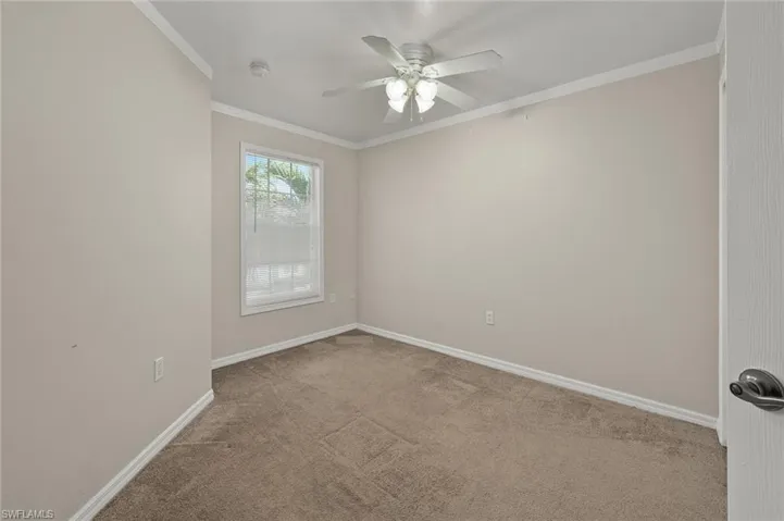 Carpeted spare room with crown molding and ceiling fan