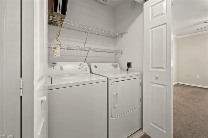 Laundry area featuring crown molding, separate washer and dryer, and light carpet