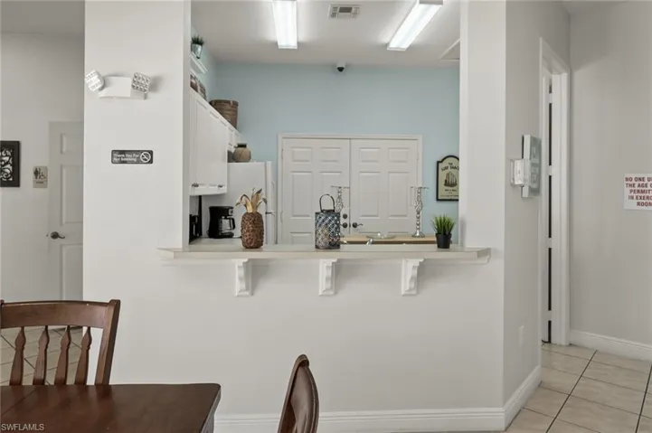 Kitchen featuring white cabinetry, a breakfast bar area, white refrigerator, light tile patterned floors, and kitchen peninsula