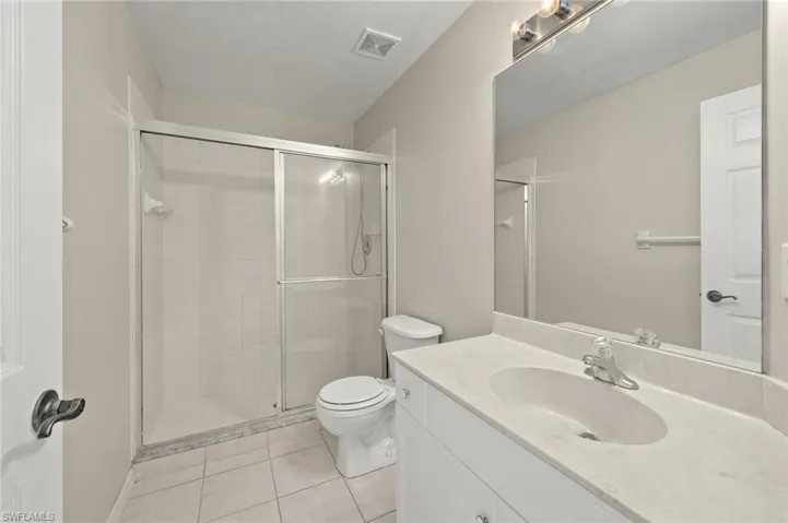 Bathroom with vanity, tile patterned floors, a shower with door, and toilet