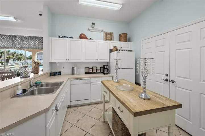 Kitchen featuring white cabinetry, white appliances, light tile patterned flooring, and sink