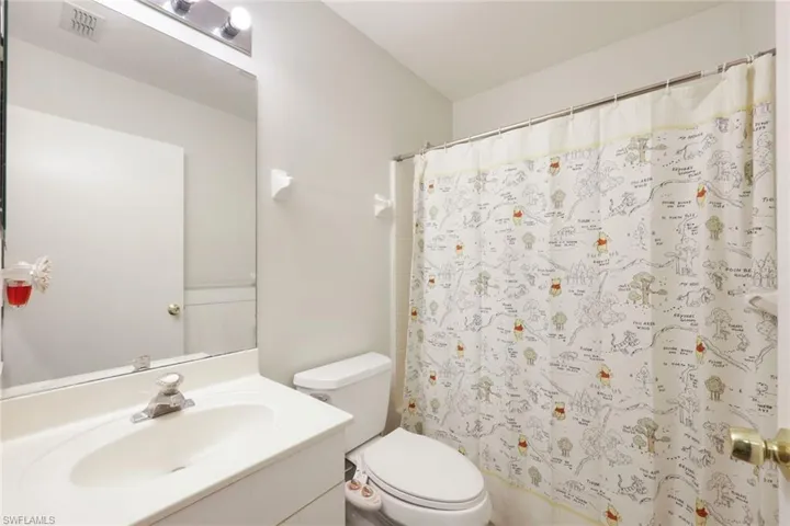 Bathroom featuring a built-in vanity with integrated sink, wall-mounted mirror, and overhead vanity lighting