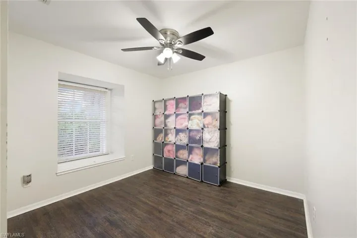 Room with wood-finish flooring, a window with blinds, a ceiling fan with integrated lighting, and neutral wall tones