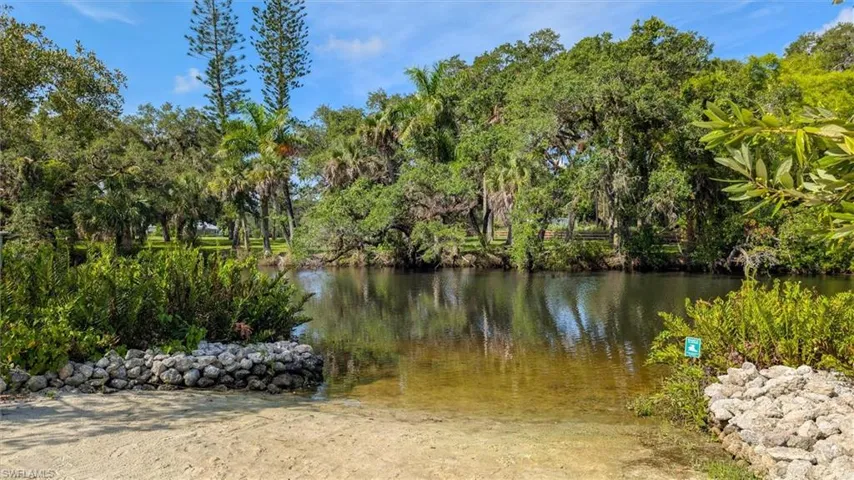 Natural water feature bordered by lush, mature trees and varied green foliage