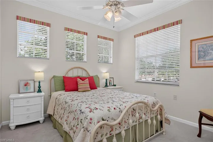 Bedroom featuring a ceiling fan with light fixture, three windows with horizontal blinds and valances, and light-toned wall paint