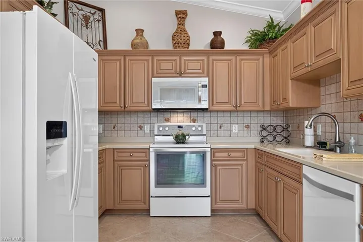Kitchen featuring wood-finish cabinetry, white appliances, and a tiled backsplash