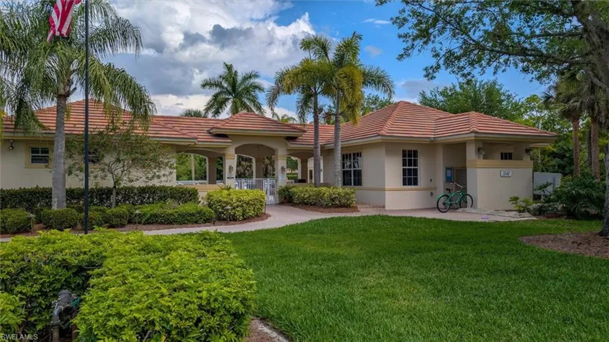Stucco building featuring a terracotta tile roof, arched entryway, and multiple windows