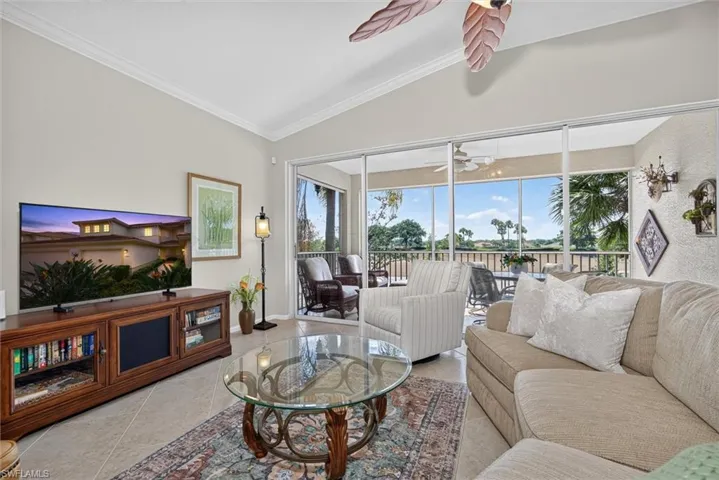 Spacious living area featuring neutral wall tones, tile flooring, and vaulted ceilings with crown molding