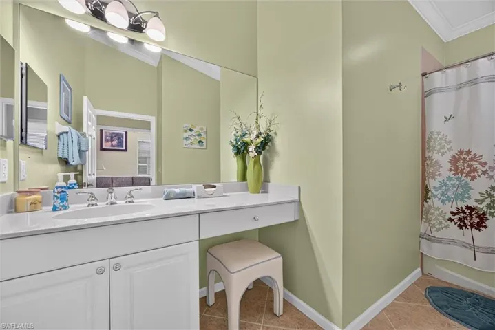 Double vanity featuring a light-toned countertop, integrated sinks, and white cabinetry