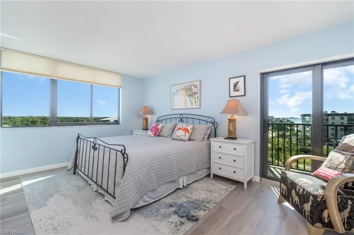 Bedroom with multiple windows, wood finished floors, and access to outside