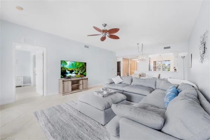 Living room with ceiling fan, hanging lights, and light tile patterned floors