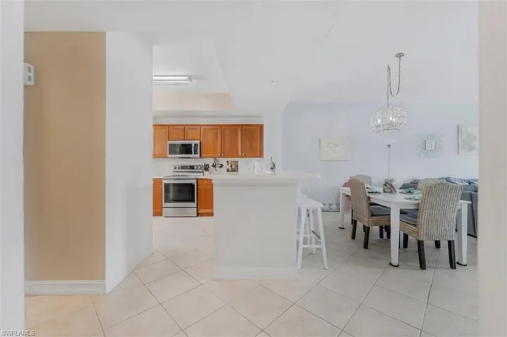 Kitchen featuring light countertops, stainless steel appliances, wood finish cabinetry, a kitchen breakfast bar, and open floor plan
