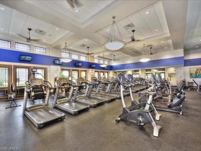 Workout area featuring ceiling fan, a towering ceiling, and coffered ceiling