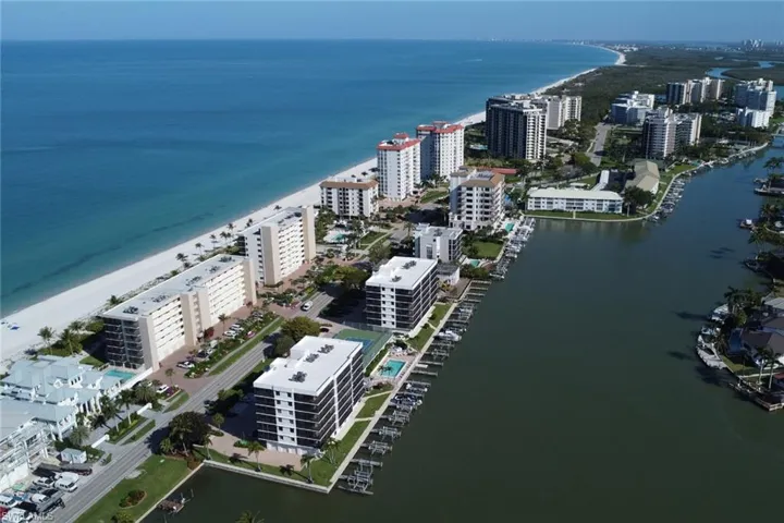 Aerial presentation of a coastal residential area featuring beachfront properties and canal-front residences with private boat docks