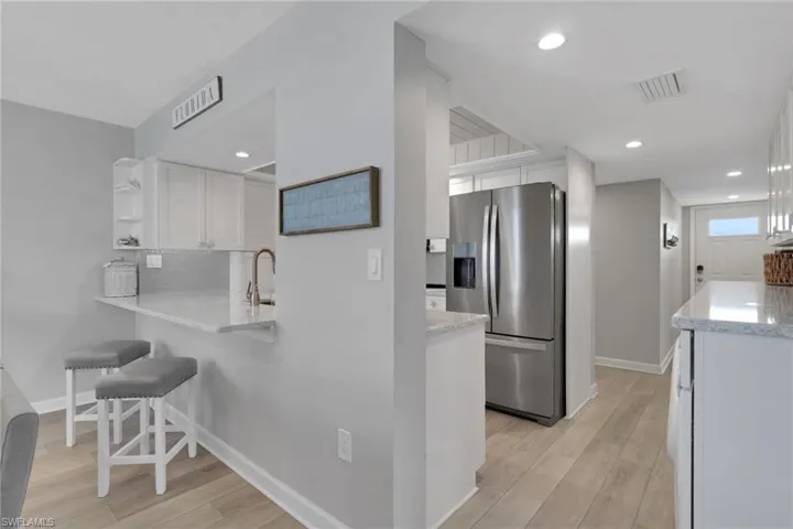 Kitchen passthrough with granite countertop, stainless steel faucet, and white shaker cabinetry