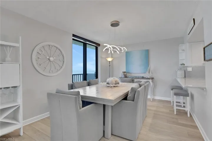Dining area featuring light wood-finish flooring, a contemporary chandelier, and direct balcony access through sliding glass doors