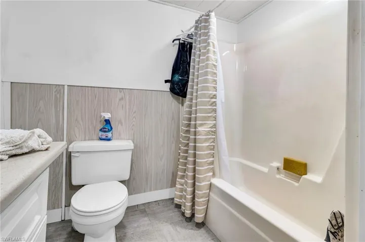 Full bath with toilet / bath combo with shower curtain, and vanity