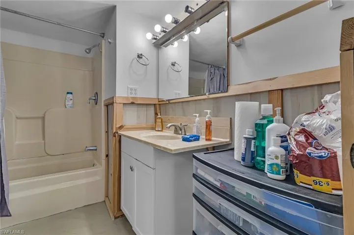 Full bath featuring shower / bath combination with curtain, concrete flooring, and vanity