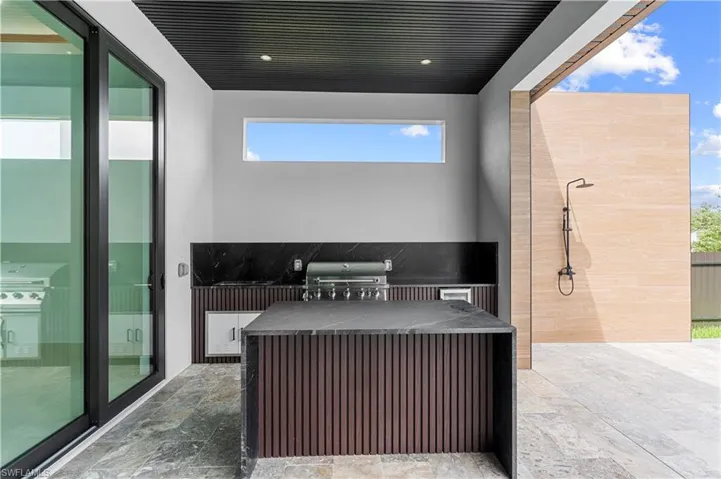 Outdoor kitchen with integrated grill, built-in cabinetry, and black countertop