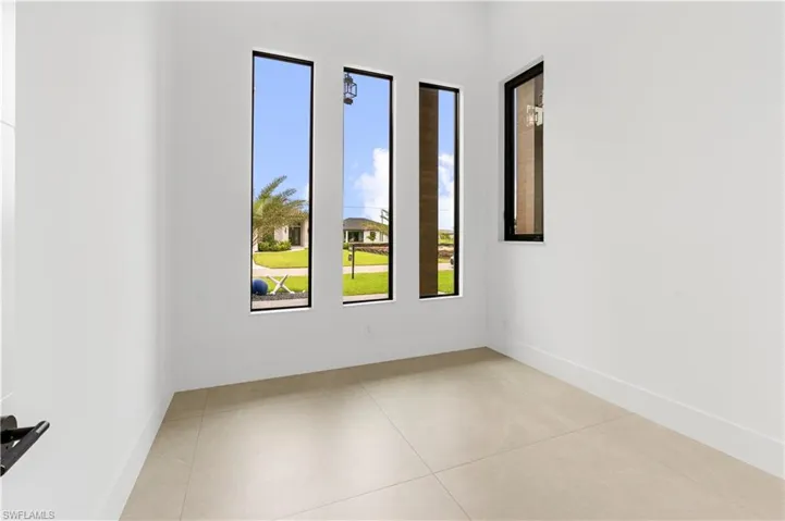 Neutral-toned tile flooring, tall vertical windows, white walls, and white baseboards