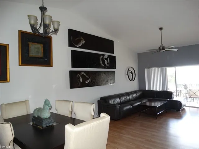 Living room featuring lofted ceiling, a ceiling fan, wood finished floors, and a chandelier