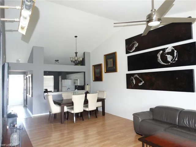 Dining room with lofted ceiling, light wood-style flooring, a chandelier, and a ceiling fan