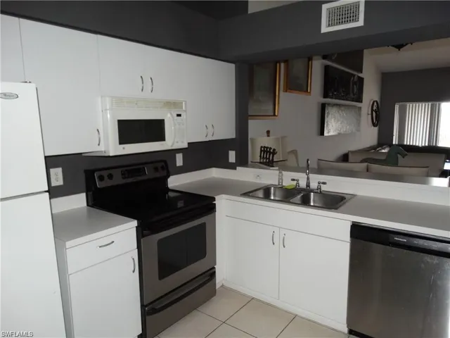 Kitchen featuring stainless steel appliances, light countertops, and white cabinets
