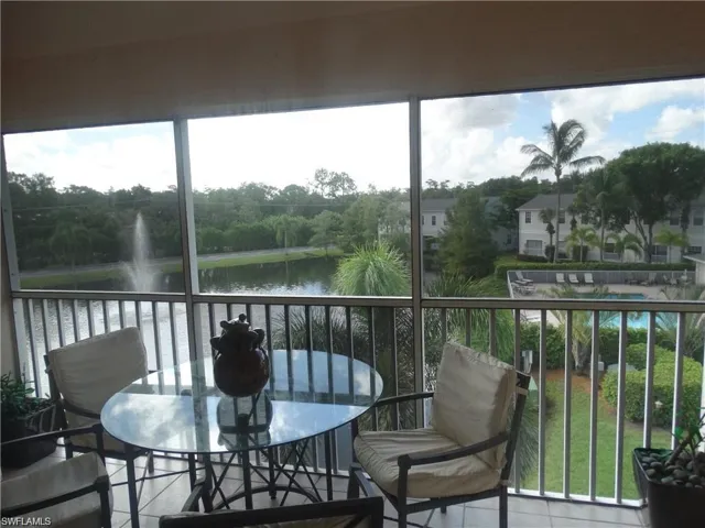 Sunroom with a water view and view of scattered trees