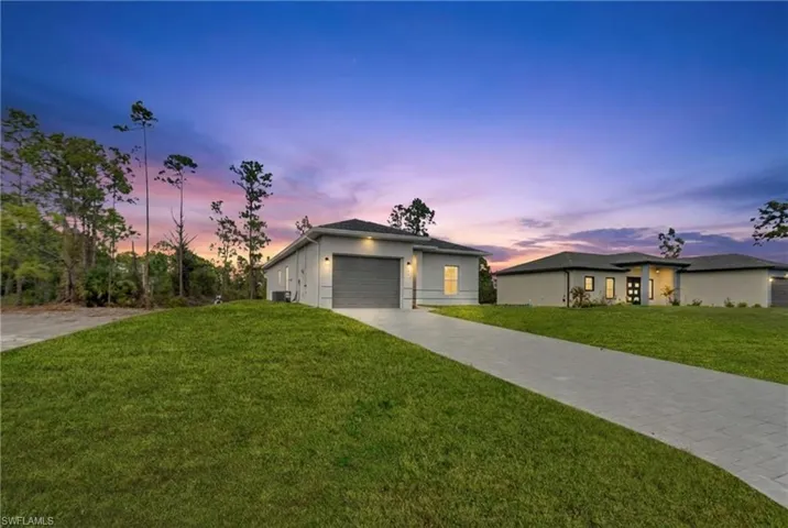 View of front of property featuring a yard, driveway, and stucco siding
