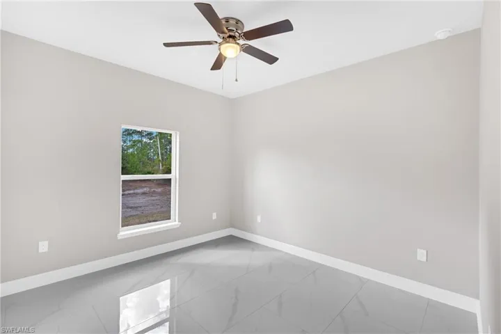 Spare room with ceiling fan and light marble finish floors