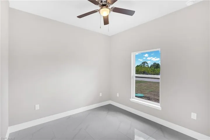 Spare room with light marble finish floors and ceiling fan